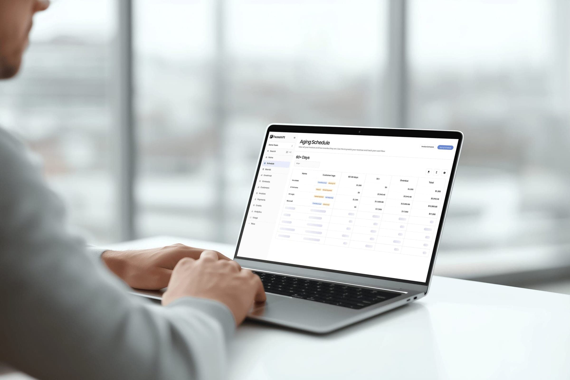 A person typing on a laptop that shows the Fazeshift aging schedule, with open invoices grouped by days past due