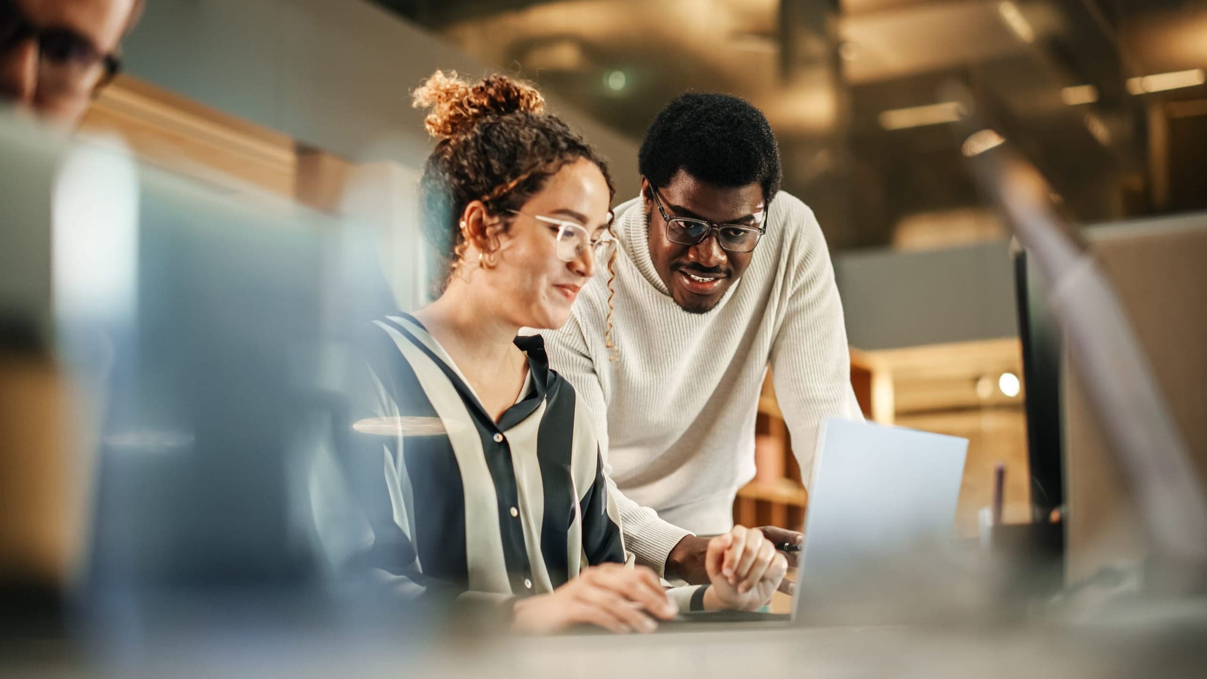 Two colleagues reviewing work together at a laptop