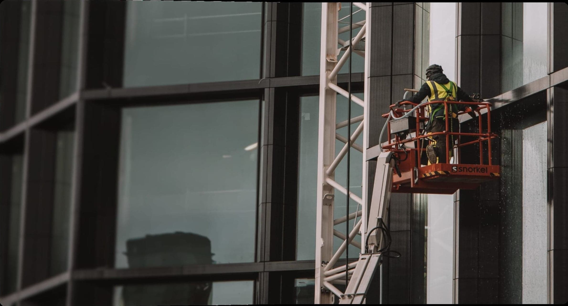 A worker on a lift installing glass on a building facade