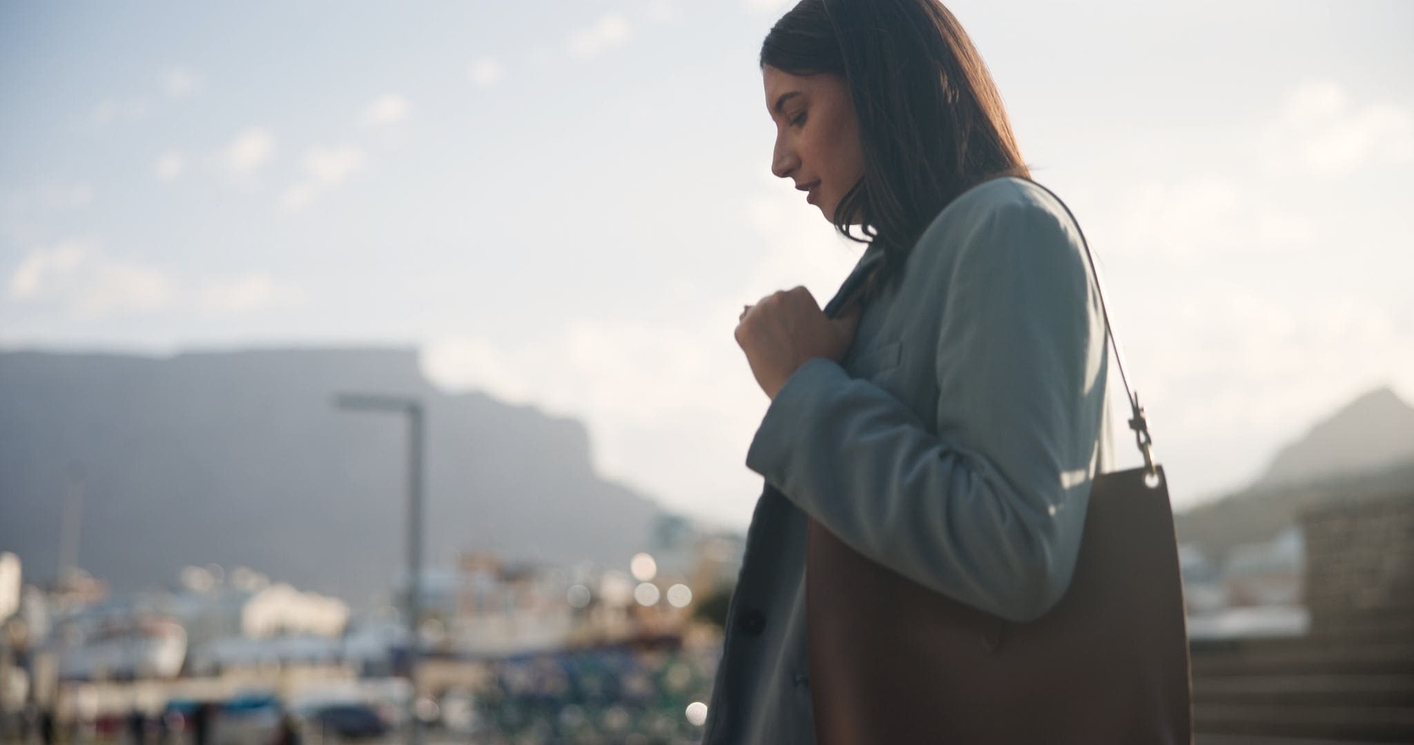 Professional walking along a waterfront with the city behind her