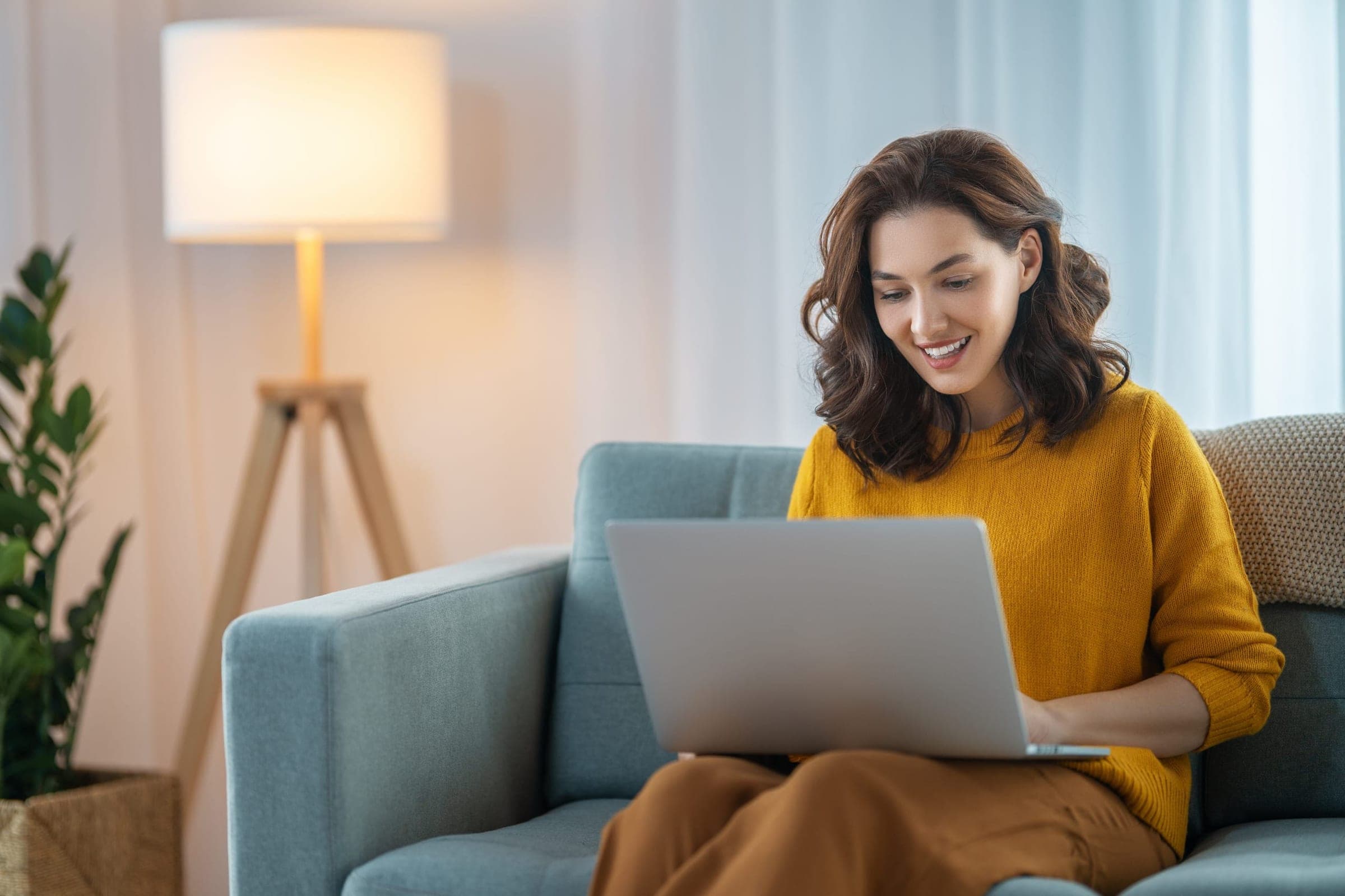 Finance team member smiling at a laptop in a bright home office