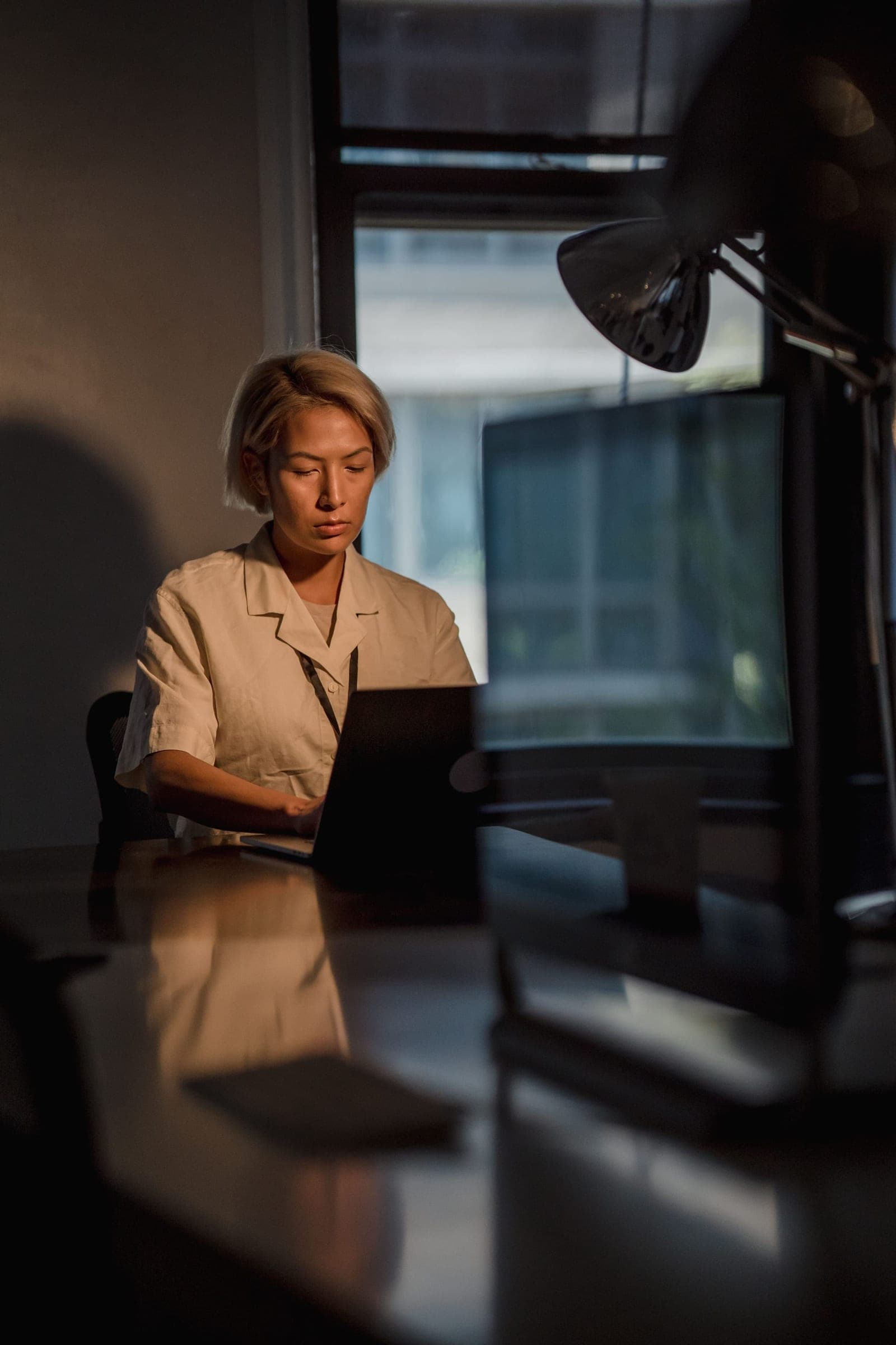 Person working at a laptop by a window in warm evening light
